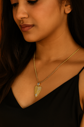 Close-up of a woman wearing a gold necklace with a heart-shaped pendant.