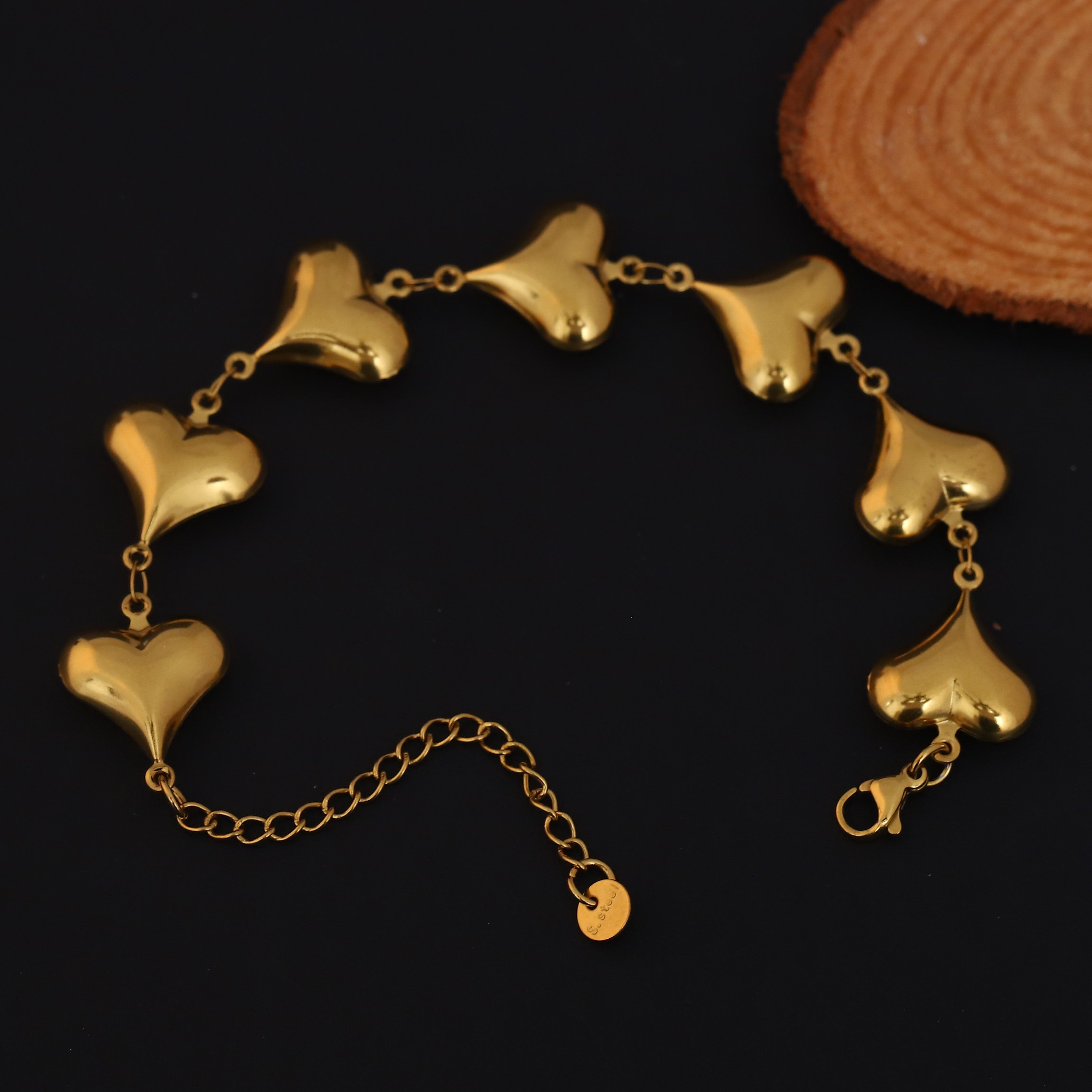 Gold bracelet with heart-shaped links on a dark background