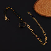Gold chain necklace on a dark surface with a wooden coaster in the background