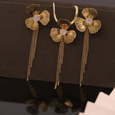 Gold floral earrings with chain details on a dark surface