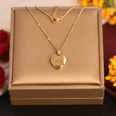 Gold heart-shaped necklace with a diamond in a gold box, surrounded by flowers.