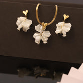 Jewelry set with white floral earrings and a gold necklace on a black background