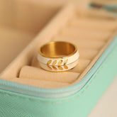 Gold ring with leaf design on a light green jewelry box