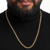 Gold chain necklace worn by a person in a black turtleneck against a white background