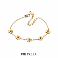 Gold bracelet with floral designs on a white background, branded 'DIE TREZA'.