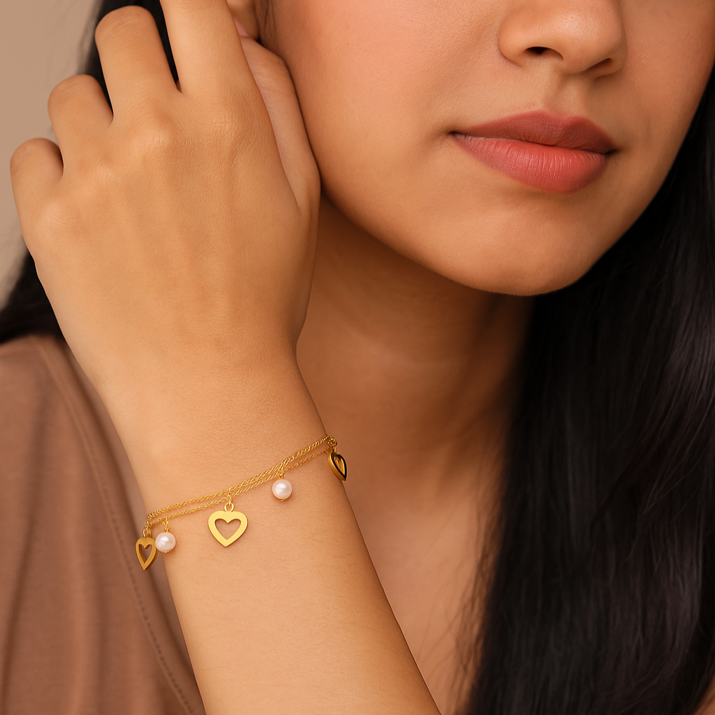 Woman wearing a gold bracelet with heart charms on a neutral background