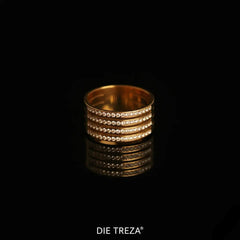 Gold ring with embedded stones on a black background, branded 'DIE TREZA'.