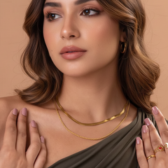 Woman wearing gold jewelry against a beige background
