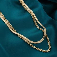 Gold chain necklace on a teal fabric background