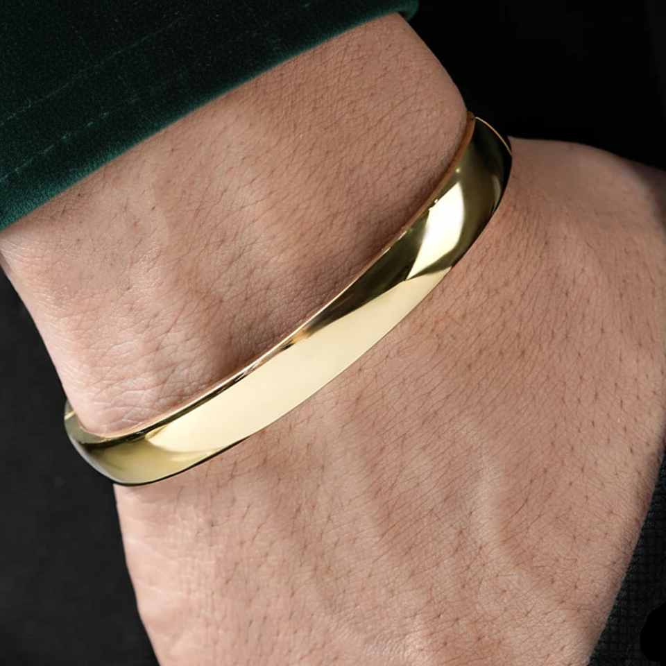 Gold bracelet on a person's wrist with a dark background