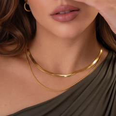 Woman wearing a gold necklace with a neutral background