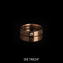 Rose gold ring with a diamond on a black background, branded 'DIE TREZA'.