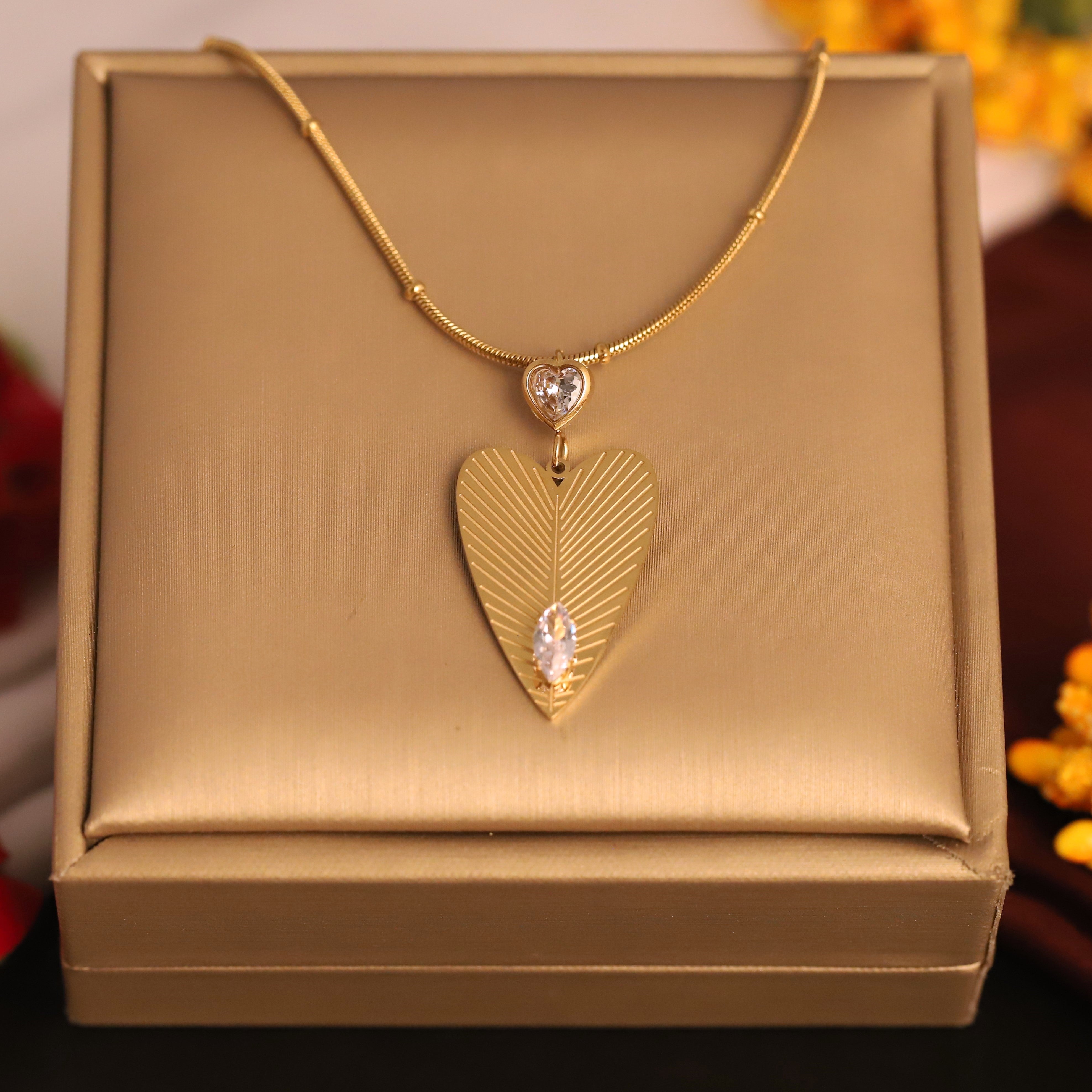 Gold necklace with a heart-shaped pendant on a gold box