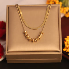 Gold necklace on a gold jewelry box with flowers in the background