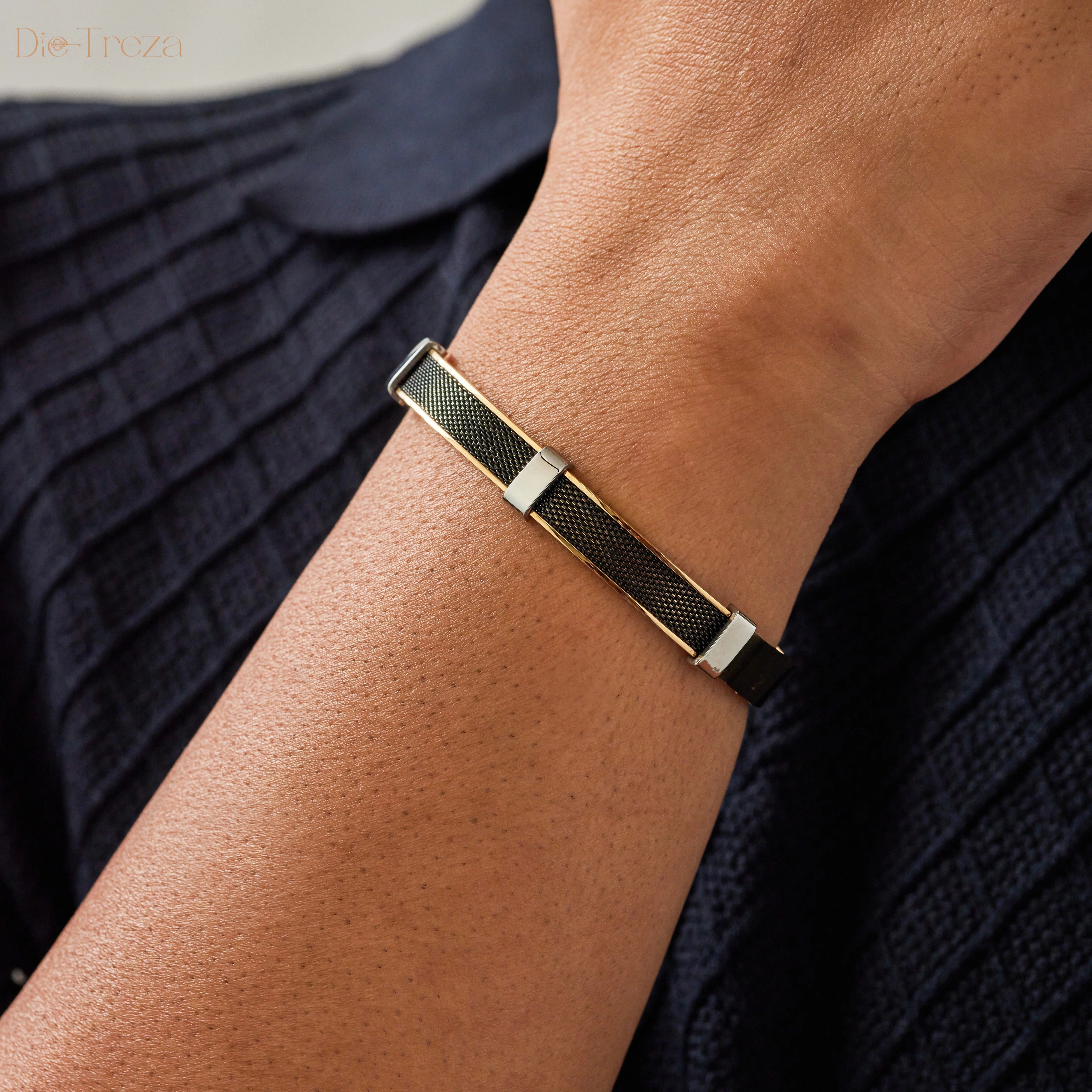 Close-up of a person's wrist wearing a gold and black bracelet against a dark background.